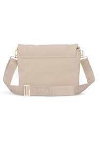 Beige színű keresztpántos táska, strukturált dizájnnal, szövettextúrával, fedeles záródással, és logózott pánttal arany színű hardver részletek kíséretében.