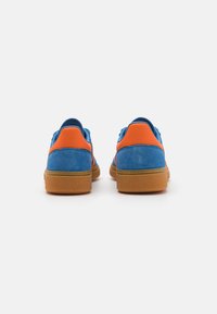 Blå ruskinnsneakers med oransje detaljer og en teksturert tan gummisåle, med lavprofil design og polstret krage for komfort.