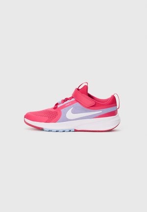 Basket de sport Nike rose et violette avec un swoosh blanc, tige en maille, bande Velcro et semelle blanche rembourrée sur fond uni.