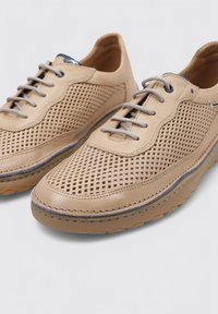Zapatos de cuero beige con diseño perforado, agujetas grises y suelas de goma. Presentan detalles de costura y un ligero tacón para mayor comodidad.