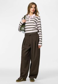 Roosa ja tume-rohelise triibuline pika varrukaga polo-särk, kombineeritud pruunide pliseeritud laia säärega pükstega. Täiendatud rohelise käekoti ja roheliste kingadega.