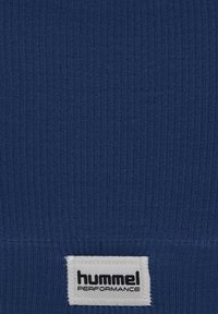 Marinblå ribbad sporttröja med en vit tygetikett längst ner med texten "hummel PERFORMANCE". Mjuk textur, åtsittande design.
