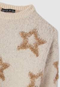 Maglione beige chiaro con una texture a maglia larga, caratterizzato da motivi a stella marroni. Scollo tondo a coste e tessuto morbido per il massimo comfort.