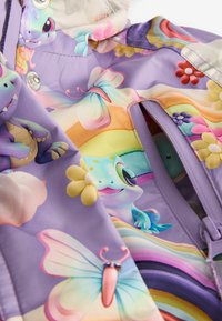 Lila Regenmantel mit bunten Cartoon-Mustern von Tieren und Blumen, mit Druckknopfverschlüssen und Reißverschlussöffnungen für die Taschen.