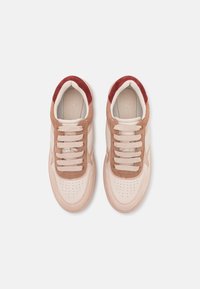 Helle beige und braune Sneakers aus Wildleder und Leder, mit runden Schnürsenkeln, perforiertem Zehenbereich und roten Akzenten an der Ferse.