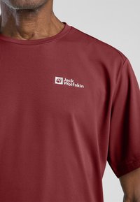 Rode T-shirt met korte mouwen van gestructureerde stof, voorzien van een wit logo op de linkerborst, ronde halslijn en een ontspannen pasvorm.