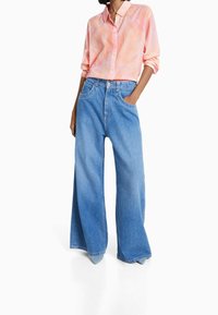 Lichtroze gestreepte overhemden met opgerolde mouwen, gecombineerd met wijde blauwe denim jeans met voorzakken en een relaxte pasvorm.