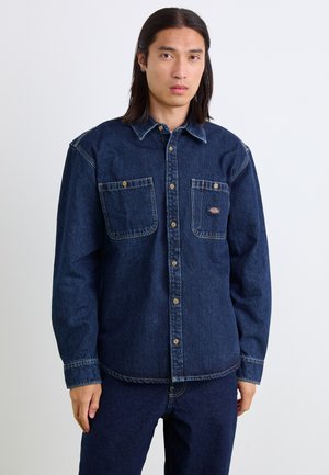 Denim shirt in dark blue with a button-down collar, two chest pockets, and golden buttons. Soft texture and classic fit.