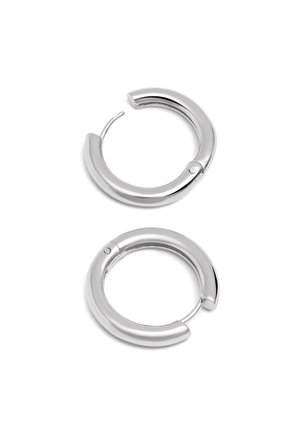 Paire de boucles d’oreilles créoles épaisses et lisses en argent avec fermoir à charnière, présentée sur fond blanc.