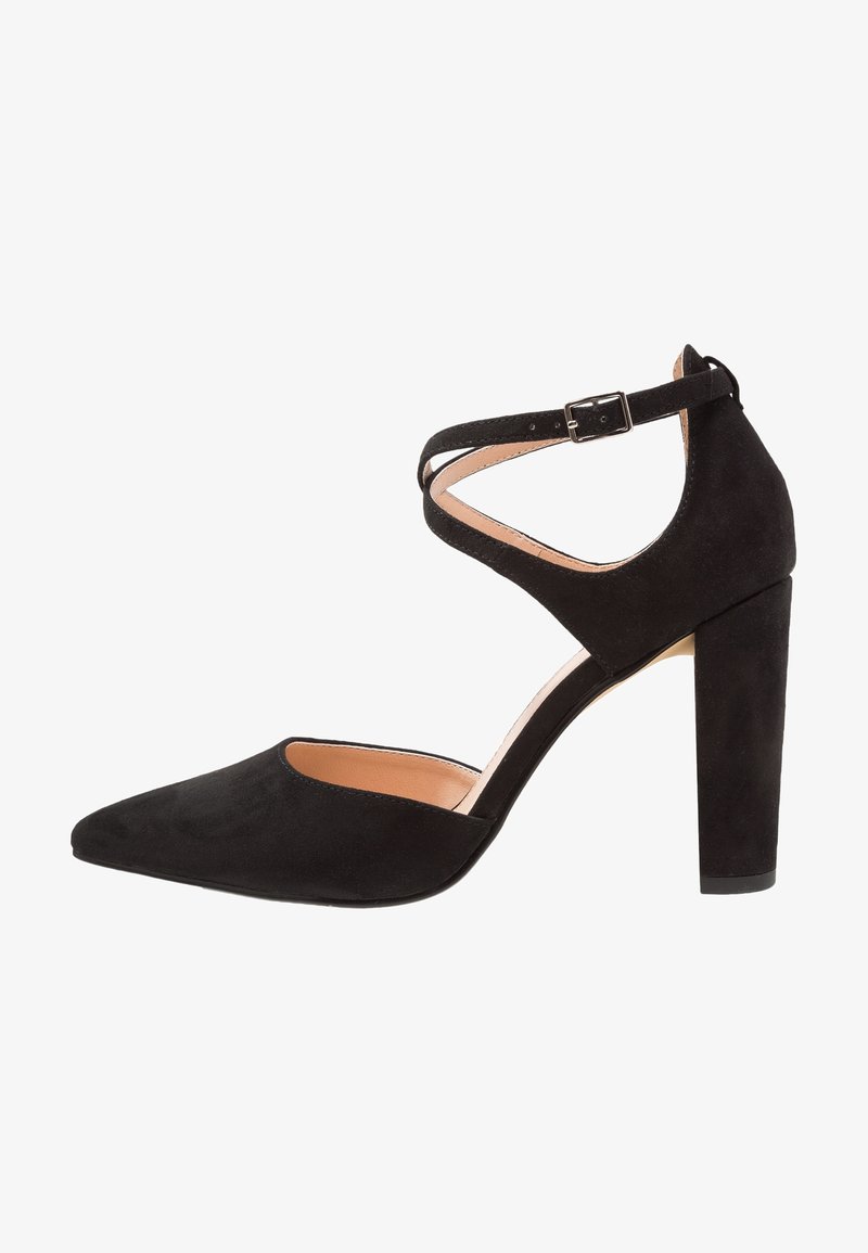 Chaussure à talon haut en daim noir avec un bout pointu, une bride de cheville et un talon épais. Texture lisse et accents de design minimaliste.