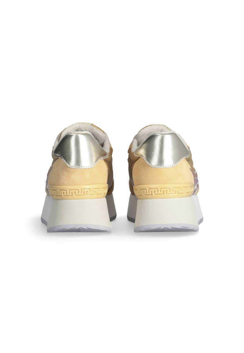 Par de deportivas beige y plateadas metálicas vistas desde atrás, con suelas gruesas de plataforma blanca con patrones decorativos.