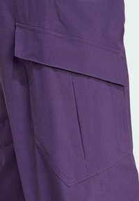 Violet cargo trousers featuring a large front pocket with a fold-over flap, made from lightweight fabric with a smooth texture.