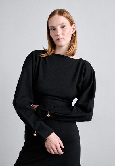 Black dress with a fitted silhouette, rounded neckline, puffed long sleeves, and gold ball accents at the cuffs, made from a textured fabric.