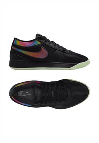 Sneakers nere Nike con tomaia in mesh, dettagli colorati iridescenti, lacci piatti e suola in gomma traslucida. Logo Swoosh ben visibile.