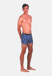 Boxers bleu avec un imprimé animal ludique, dotés d'une taille noire avec le logo "WAXX". Fabriqués en tissu doux et extensible.