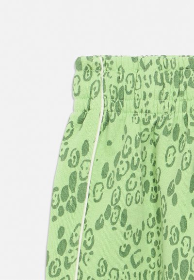 Zelená tkanina s tmavě zeleným leopardím vzorem a elastickým pasem s bílým lemem podél bočního švu.