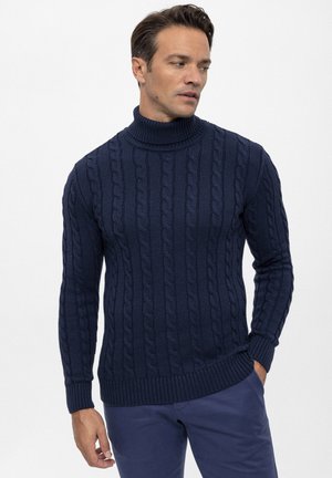 Granatowy sweter z golfem wykonany z dzianiny, z wyraźnym wzorem w warkocze. Ściągacze przy mankietach i dolnym końcu dodają struktury i tekstury.