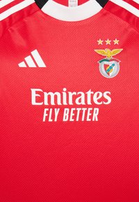 Raudona futbolo marškinėliai, pagaminti iš tekstūruoto audinio. Juose yra baltas Adidas logotipas, tekstas "Emirates FLY BETTER" ir Benfica emblema su trimis auksinėmis žvaigždėmis.