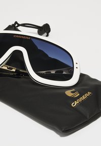 Occhiali da sole Carrera neri e oro con montatura bianca, lenti blu sfumate e una morbida custodia nera. Logo distintivo sulla custodia.
