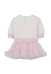 Haut en tricot blanc avec des accents roses, présentant trois boutons dans le dos. Une jupe en tulle rose superposée avec des bords froncés est attachée.