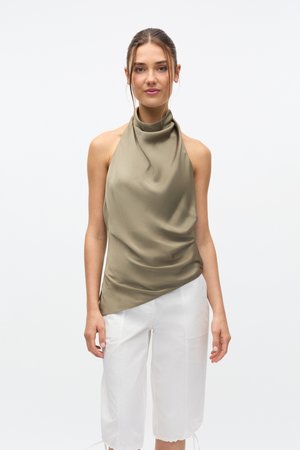 Haut dos nu vert olive à design drapé, confectionné en tissu lisse. Associé à un pantalon blanc raccourci avec poches latérales et ourlet effiloché.