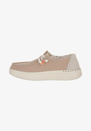Chaussure en toile beige avec des lacets blancs, panneau de talon contrastant et couture latérale texturée. Présente une semelle intérieure légèrement rembourrée avec un motif géométrique.