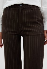 Bruna ränderade byxor i texturerat tyg, med knäppning fram, framfickor och raka ben.