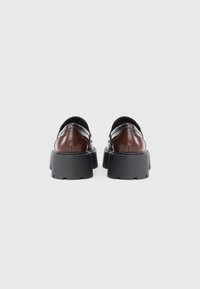 Bruine leren plateau schoenen met een ronde neus en zwarte rubberen zolen. Bevat een bandje over de voetboog en heeft een gladde afwerking.