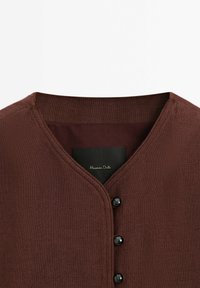 Brun stickad kofta med V-ringning, tre svarta knappar och en etikett med "Massimo Dutti" i kursiv. Tyg med struktur.