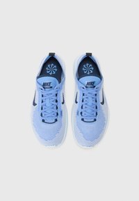 Lyseblå Nike Free sneakers med åndbart mesh-materiale, snøresystem, mørkeblå accenter og en mønstret indersål. Enkelt, moderne design.