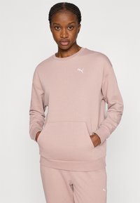 Ανοιχτό ροζ φούτερ με στρογγυλή λαιμόκοψη, ριμπ μανσέτες και μπροστινή τσέπη. Διαθέτει μικρό λευκό λογότυπο Puma στο στήθος. Μαλακό, υφασμάτινο ύφασμα με υφή.