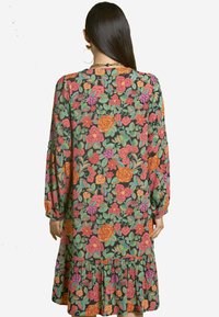 Blumenkleid aus Stoff mit lebhaften Mustern in Rot, Pink und Grün auf schwarzem Hintergrund, mit einem gerafften Saum und Ballonärmeln.