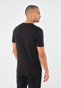 Schwarzes T-Shirt mit kurzen Ärmeln, aus Baumwolle gefertigt, mit Rundhalsausschnitt. Der Stoff hat eine glatte Textur und eine figurnahe Silhouette.