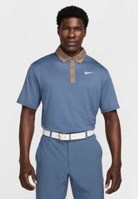Vīriešu golfa polo krekls gaiši zils ar brūnu apkakli un pogu detalizāciju. Uz krūtīm ir balts Nike logo. Balti jostas akcenti.