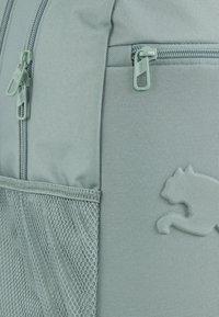 Heledad hallhalli selgehall seljakott, mis on valmistatud tekstureeritud kangast, millel on kaks tõmbluku, võrkkotike küljel ja silmapaistvalt tõstetud logo.