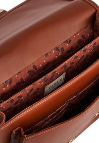 Smeđa kožna torba otvorena da pokaže cvjetni platneni oblog, unutarnji zipni džep i oznaku s natpisom "FABLE".