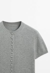Cardigan lavorato a maglia grigio chiaro con maniche corte, scollatura rotonda e chiusura frontale con bottoni rotondi equidistanti.