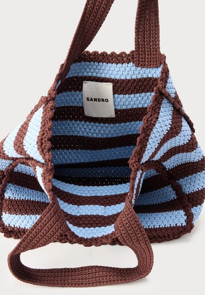 Χειροποίητη υφαντή τσάντα ώμου με εναλλασσόμενες καφέ και ανοιχτομπλε ρίγες, φαρδιές καφέ χειρολαβές και εσωτερική ετικέτα με την επιγραφή «SANDRO».