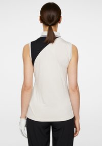 Ärmförsedd golfpolo i beige och svart med färgblockerande design, med krage och texturerad tyg.