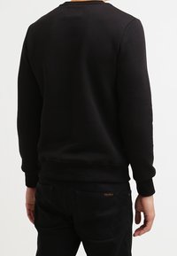 Sweatshirt noir à col rond avec des manches longues, fabriqué en tissu doux, présentant des poignets côtelés et un ourlet droit.