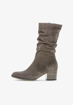 Stivale alla caviglia marrone slouchy realizzato in morbida suede con tacco a blocco e punta rotonda. Presenta variazioni di texture e un design a bassa asta.