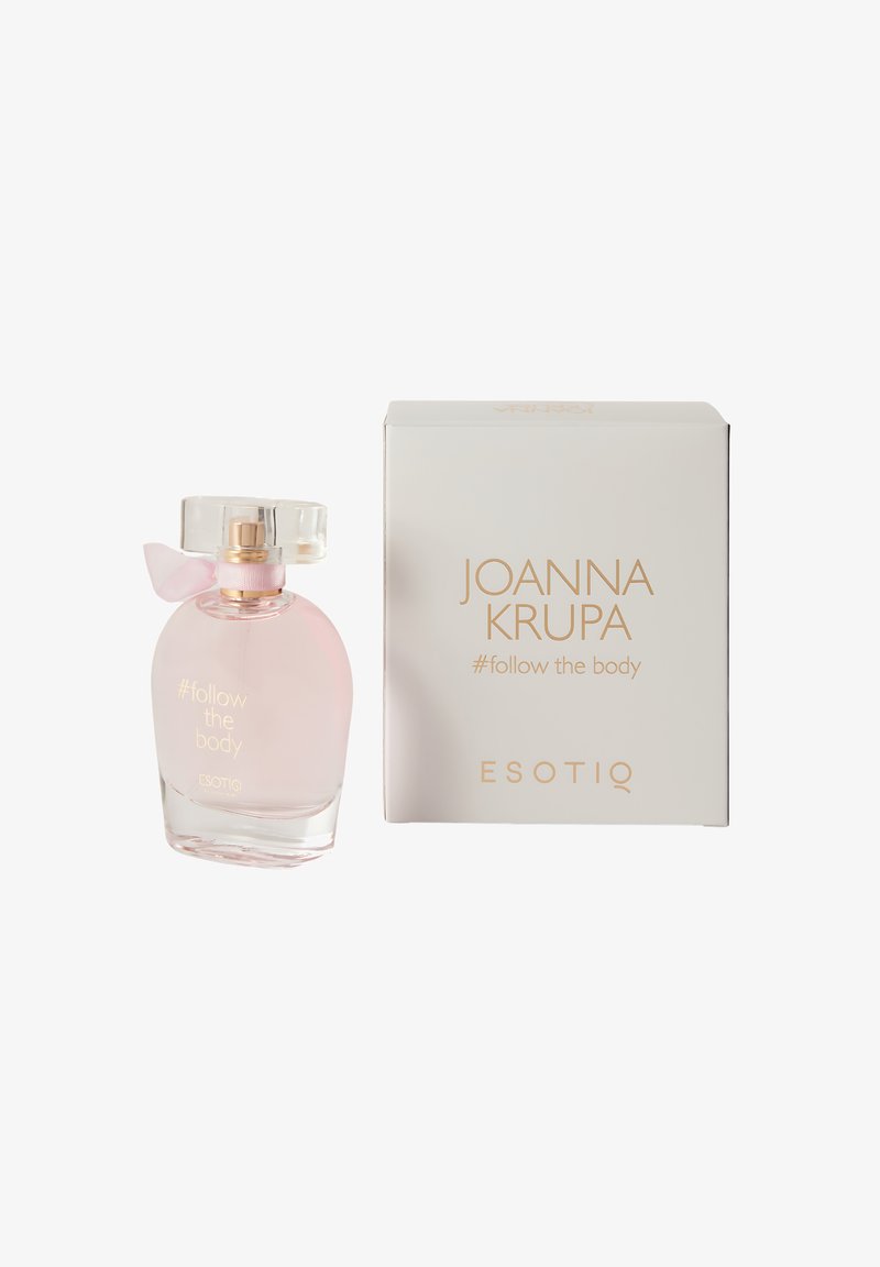 Przezroczysta butelka na perfumy z delikatnie różowym płynem, o okrągłym kształcie, z przezroczystą zakrętką i przewiązana różową wstążką. Zapakowana w białe pudełko.