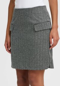 Hosenrock mit Fischgrätenmuster in Grau, ausgestattet mit zwei seitlichen Taschen, einer taillierten Passform und einem geraden Schnitt, der oberhalb des Knies endet.