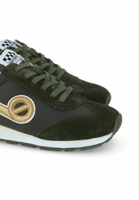 Dunkelgrüne Sneaker mit einem strukturierten Wildleder-Obermaterial, schwarzen Stoffpaneelen, weißer Sohle und einem goldenen, runden Logo an der Seite, mit grünen Schnürsenkeln.