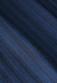 Marineblauwe stof met verticale strepen in verschillende tinten. De geweven textuur creëert een subtiele glans, geschikt voor kleding of stoffering.