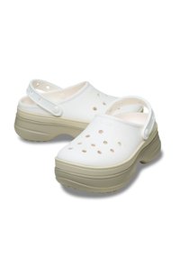 Zoccoli bianchi Crocs con fori di ventilazione, suola piatta beige, cinturino regolabile sul tallone e superficie in gomma liscia.