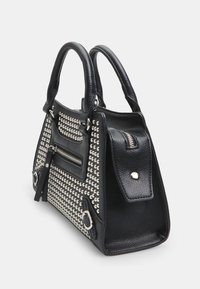 Bolso de mano de cuero negro con tachuelas plateadas, que presenta dos asas, un bolsillo delantero con cremallera y una forma estructurada. Superficie texturizada con detalles de metal.
