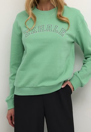 Felpa verde menta con la scritta "EXHALE" in un carattere sp bold. Presenta polsini e orlo a costine, una texture morbida, vestibilità rilassata e scollatura a girocollo.