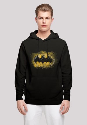 Black hoodie featuring a graphic of the Batman logo in yellow with artistic splatter details. Front kangaroo pocket and drawstring hood.