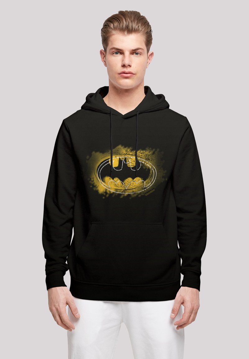 Svart hettegenser med et grafisk av Batman-logen i gult, med kunstneriske sprutdetaljer. Frontlomme og hette med snøring.